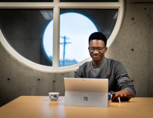 A student working on his computer in a meeting room