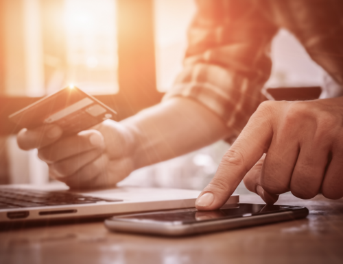 A man using a phone calculator while holding a credit card